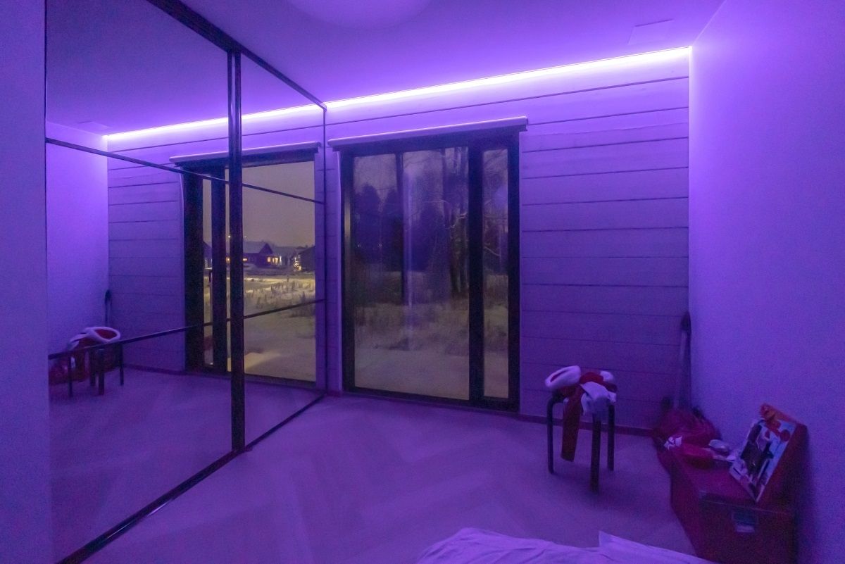 Atmosfera viola intenso in una stanza per bambini con una striscia led RGB indiretta sul bordo del soffitto e della parete